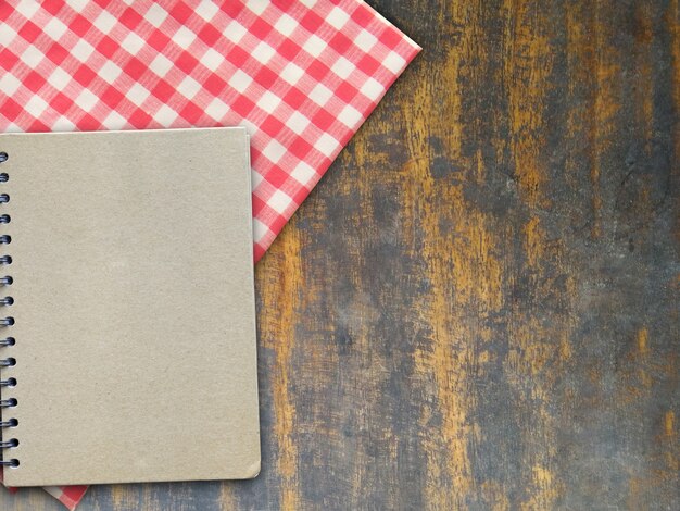 Copy space book and plaid of red and white on wooden table. business concept