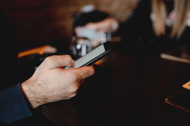 Copi la mano dell'uomo irriconoscibile del primo piano dello spazio che tiene uno smartphone che legge la carta del menu del cibo del ristorante in linea.