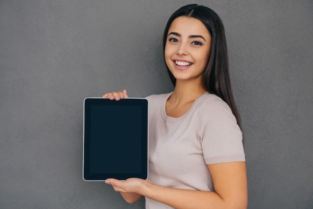 Copy space on her tablet. Beautiful young woman holding digital tablet and