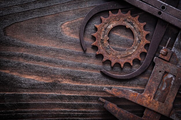 Copy space image of rusted measuring calipers with gear wheel on vintage dark wooden surface construction concept