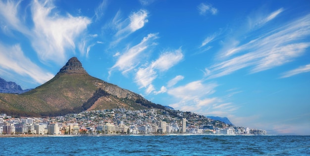 Скопируйте космическую панораму морского пейзажа с облаками, голубым небом, отелями и жилыми домами в Си-Пойнт, Кейптаун, Южная Африка, гора Львиная голова с видом на красивый полуостров голубого океана