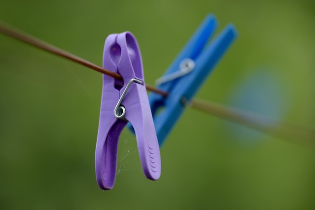 Copia spazio di mollette di plastica appese al cavo di lavaggio o alla linea della biancheria con bokeh all'esterno primo piano di ragnatele trascurate che coprono mollette viola o blu per le faccende domestiche con copyspace