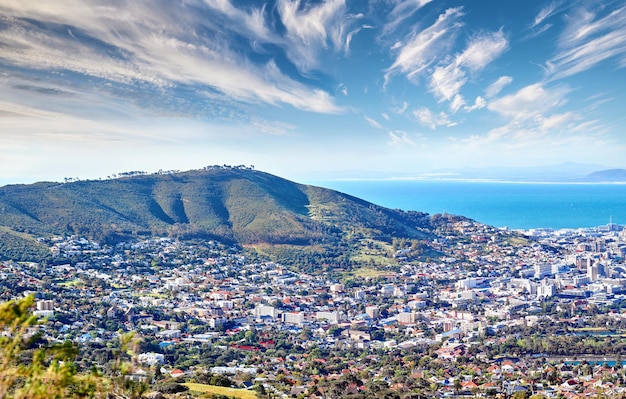 Copy space with cloudy blue sky over the view of a coastal city seen from Signal Hill in Cape Town South Africa Scenic panoramic landscape of buildings in an urban town along the mountain and sea