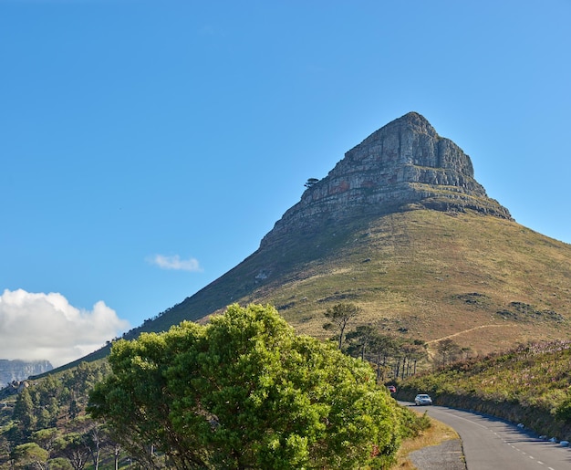 青い空を背景に南アフリカのケープタウンにあるライオンズヘッド山の美しい風景を望むコピースペース象徴的なランドマークの壮大なパノラマを旅して探索し、道路を通り過ぎる