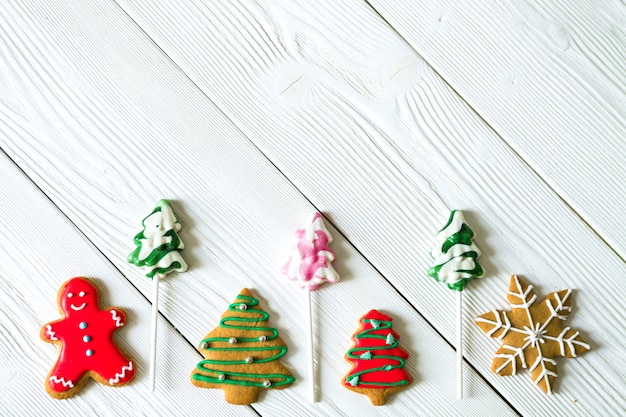 Copy space with traditional Christmas sweets on white wooden background. Candy cane, round snowflake and ginger man, star lollipop. Top view. Flat lay. Christmas concept