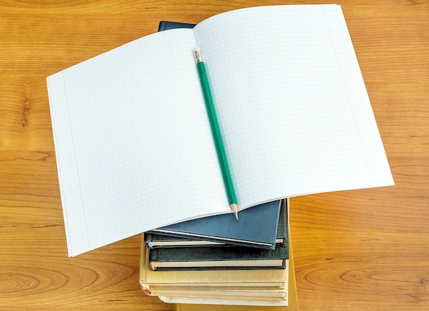 Copybook with pencil on the stack of books