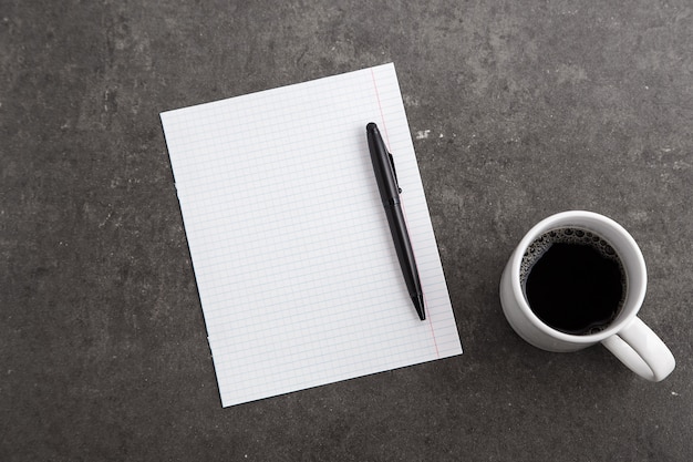 Copybooks, cup of coffee and glasses on gray marble. Space for text