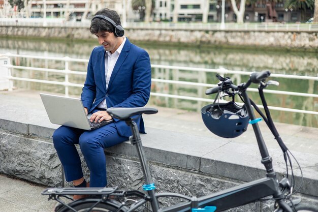 copyspace Businessman working remotely by the riverside with folding electric bike