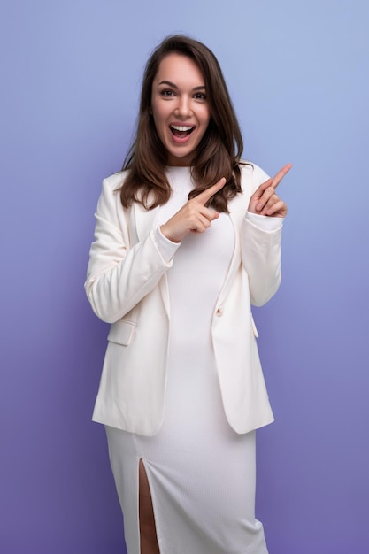 Coquette vrouw met donker lang haar in elegante witte jurk op studio achtergrond