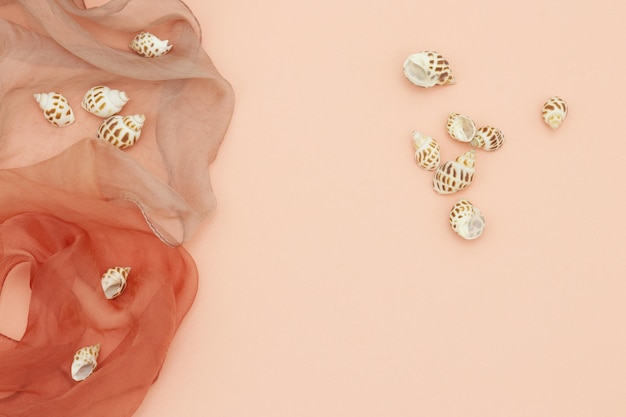 A coral fabric with shells on it and a red cloth.