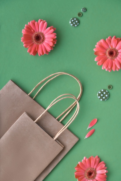 Foto fiori della margherita della gerbera di corallo e sacchetti della spesa del papper del mestiere sulla superficie del libro verde,