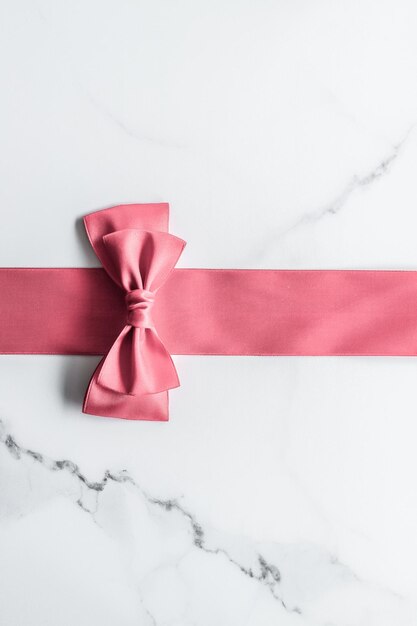 Foto nastro di seta corallo e fiocco su sfondo marmo ragazza baby shower presente e glamour moda regalo arredamento per il design flatlay vacanza marchio di bellezza di lusso