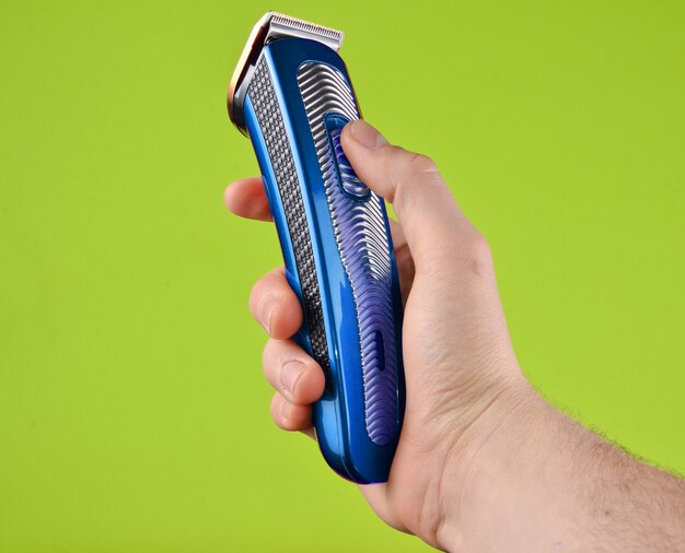 Photo cordless clipper in a male hand isolated on a green background