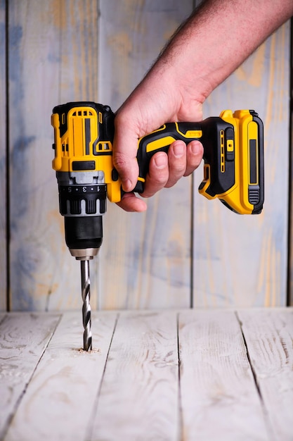 Cordless drill and a drill on a wooden background