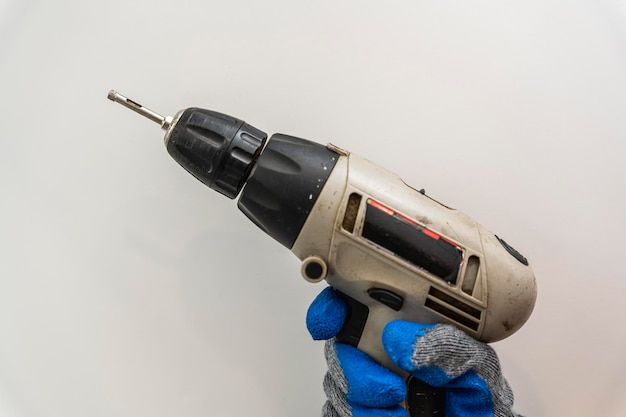 A cordless screwdriver in the hands of a man in work gloves