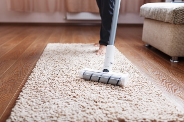 A cordless vacuum cleaner cleans the carpet in the living room with the bottom of the legs modern