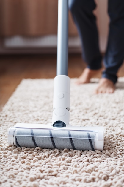 Photo a cordless vacuum cleaner cleans the carpet in the living room with the bottom of the legs.