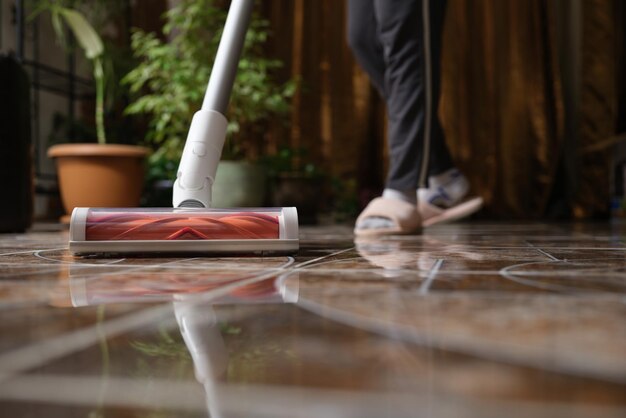 Cordless vacuum cleaner with turbo brush cleans tiles in living room