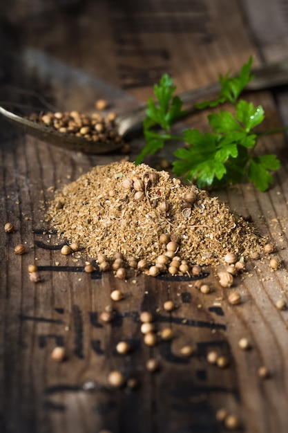 Photo coriander seeds, fresh green cilantro leaves on wooden background.