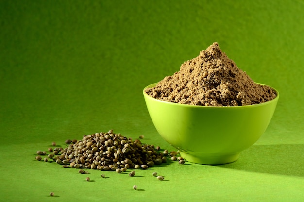 Coriander seeds and Powdered coriander in green container on green background