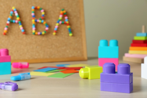 Cork board with abbreviation ABA Applied behavior analysis at table focus on colorful blocks