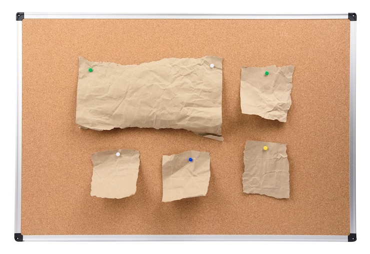 Photo cork board with aluminum frame and brown paper pieces attached board isolated on white background