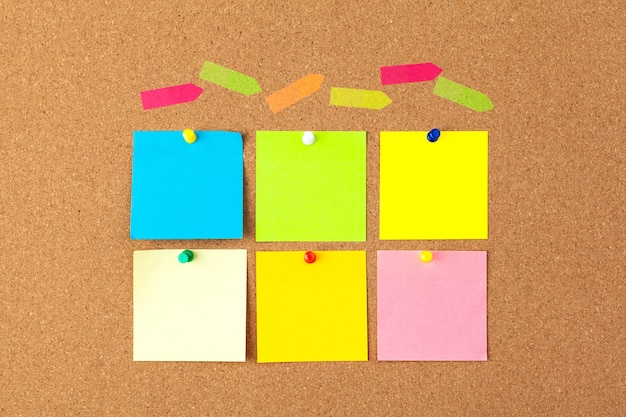 Cork board with several colorful blank notes with pins