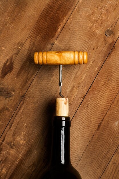 Corkscrew on a bottle of red wine and on a wooden table