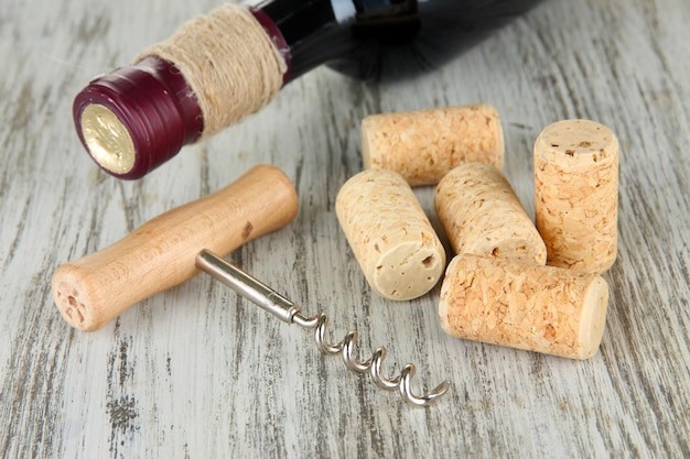 Foto corkscrew met wijnkorken en een fles wijn op een houten tafel close-up