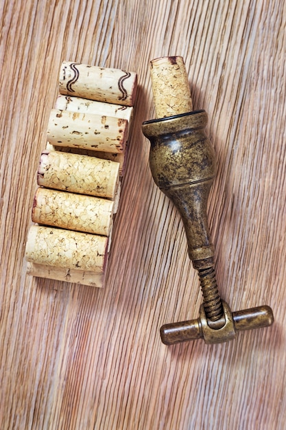 Photo corkscrew and natural corks from wine bottles on a old wooden surface.