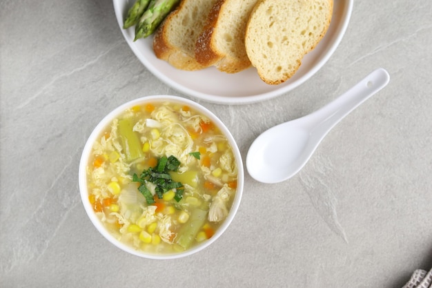 Corn and asparagus with egg drop soup in white bowl and crispy bread