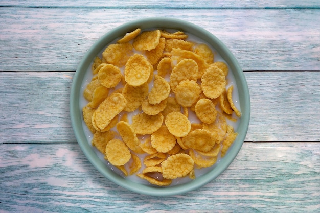 Corn cereal in a bowl with milk on blue wooden surface