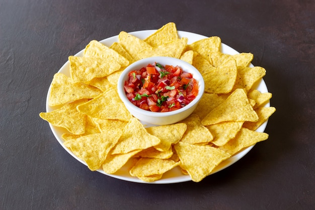 Corn chips nachos with salsa dip. mexican food. vegetarian\
food.