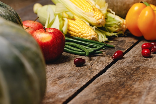 Corn cobs, apples, and pepper on wooden table