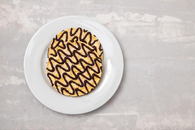 Corn crackers with lines of chocolate on white plate on grey ceramic