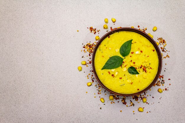 Photo corn cream soup with fresh vegetables, herbs and spices.