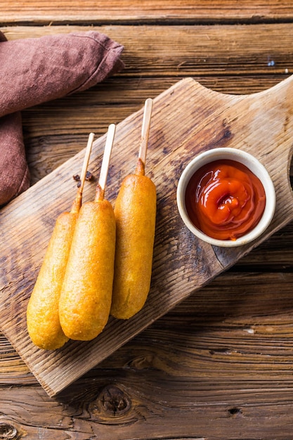 Photo corn dogs or sausage in roll with ketchup top view table scene over a wood background