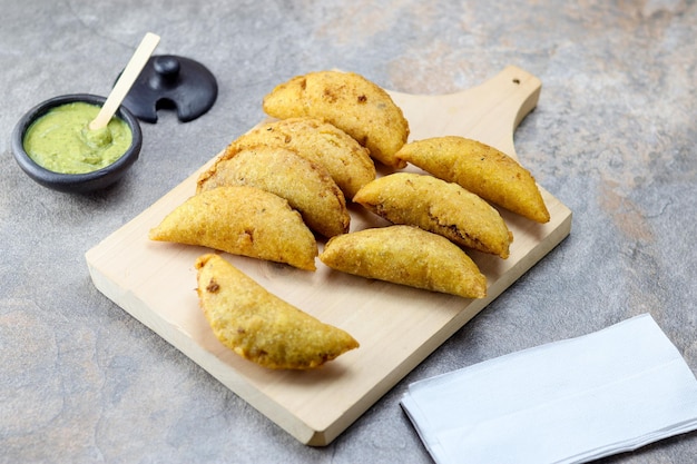 Corn empanada typical colombian food with spicy sauce on a\
chopping board