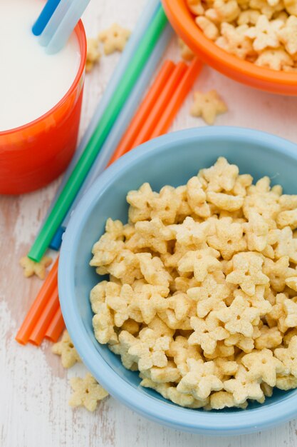 Corn flakes in blue bowl on white wood