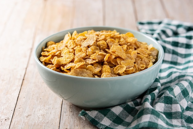 Corn flakes in a blue bowl on wooden table