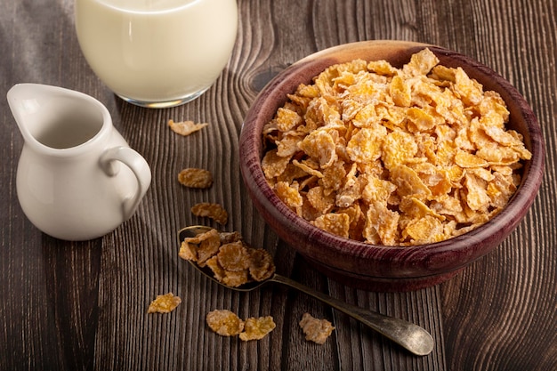 Corn flakes in bowl and glass of milk on table