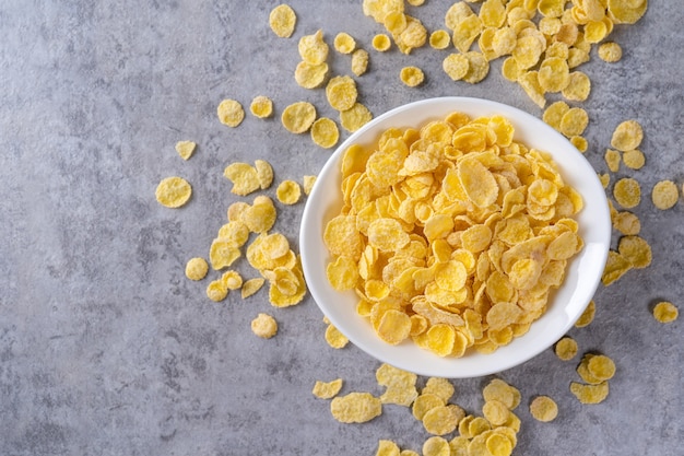 Foto dolci della ciotola dei fiocchi di mais su fondo grigio del cemento