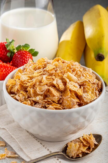 Corn flakes in the bowl with berries and milk on the table