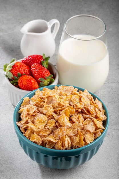 Corn flakes in the bowl with berries and milk on the table