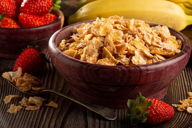 Corn flakes in the bowl with berries on the table