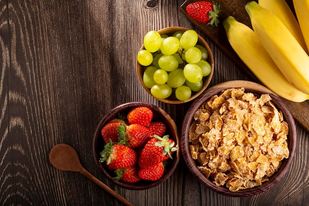 Corn flakes in the bowl with berries on the table