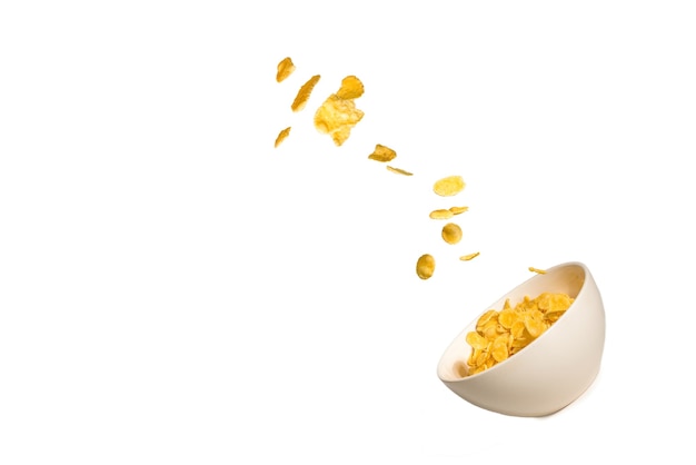 Corn flakes falling to the white bowl. Motion. Copyspace. Isolated on white.