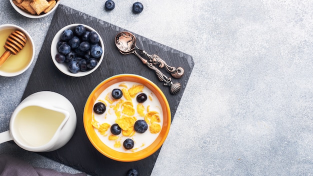 Corn flakes made from natural cereals with fresh blueberries, honey and milk. The concept of a healthy wholesome Breakfast. copy space Grey concrete table