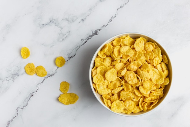 Corn flakes in white bowl on marble table