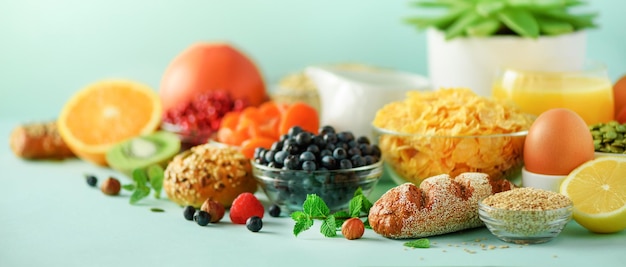 Photo corn flakes with milk fresh berries yogurt boiled egg nuts fruits orange banana peach for breakfast on blue background copy space healthy food concept